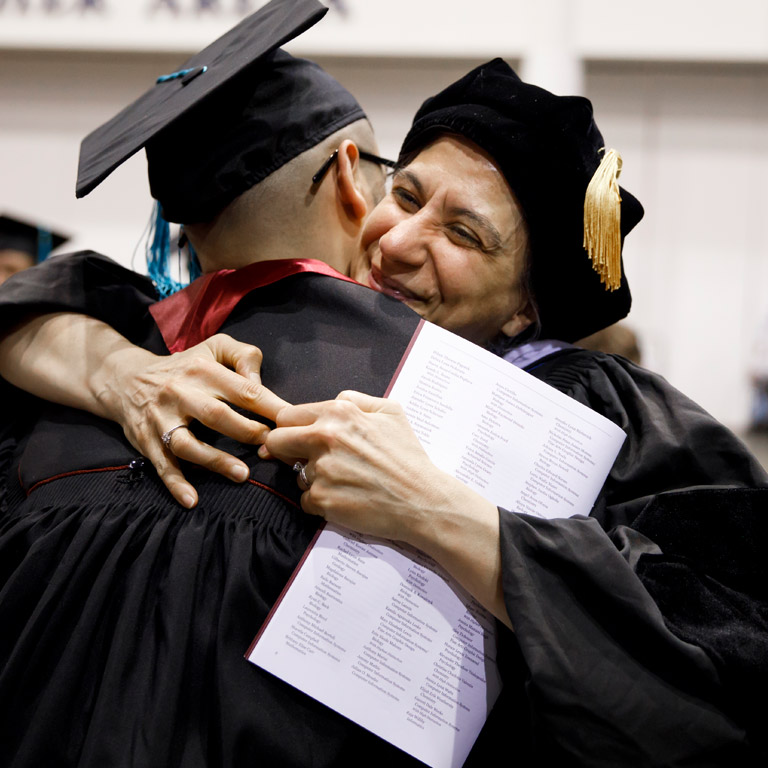 A professor hugs a student