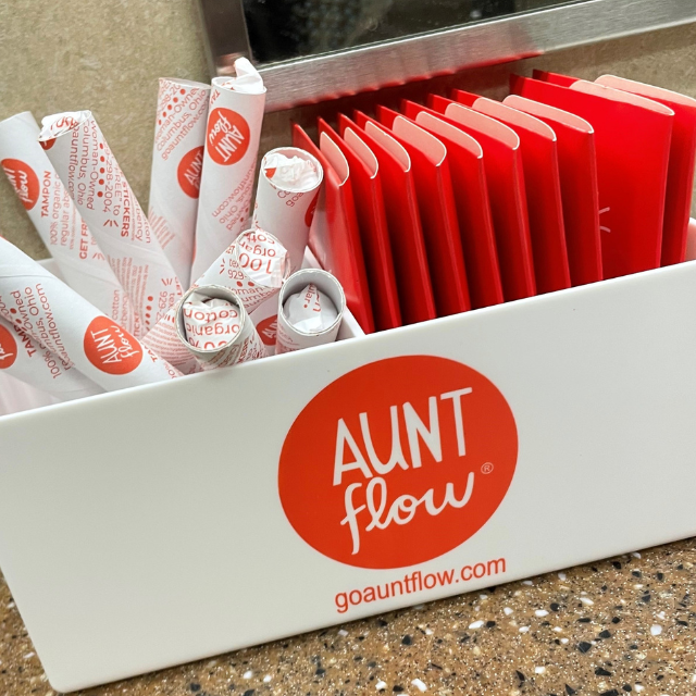 Feminine products in a white bin that says Aunt Flow.