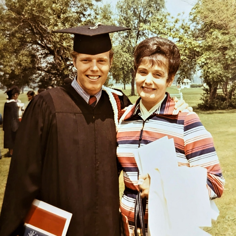 An aged photo of a man in a graduation cap and gown and a woman smiling.