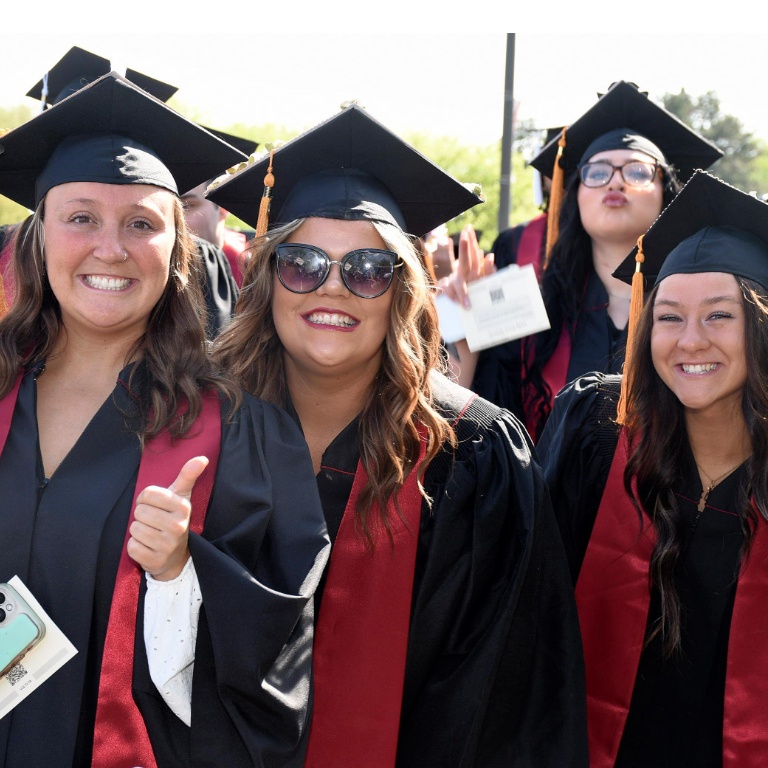 A group of female students in graduation caps and gowns smiling.