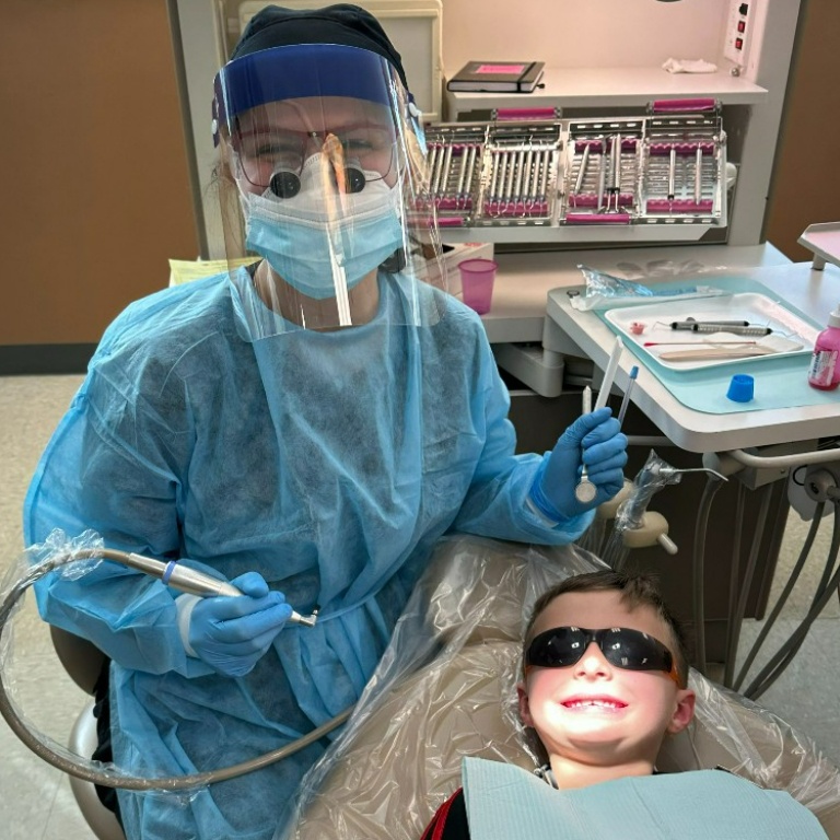 A dental hygienist cleans a child's teeth.