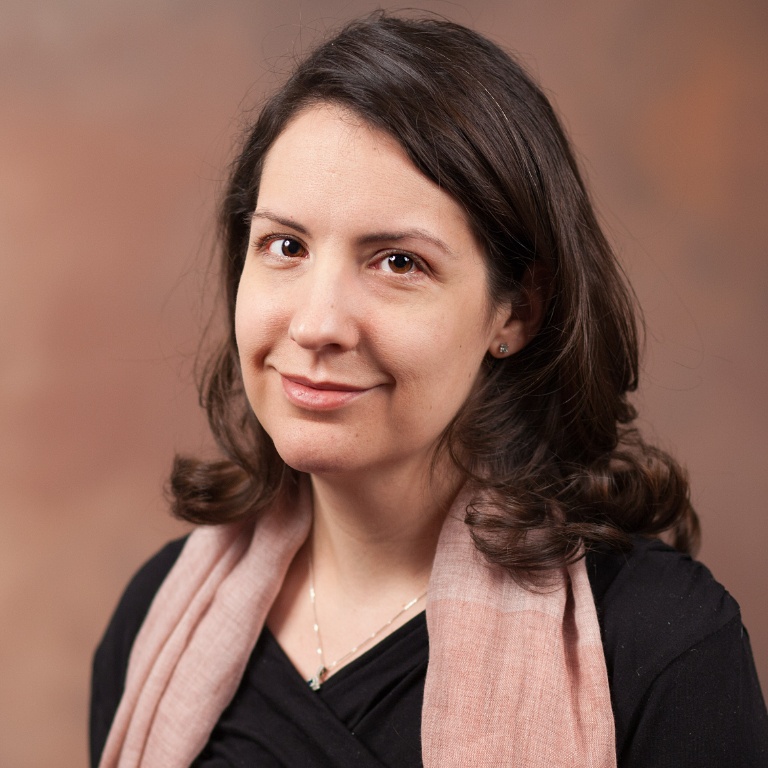 Professional photo of a female faculty member smiling in front of a brown background.