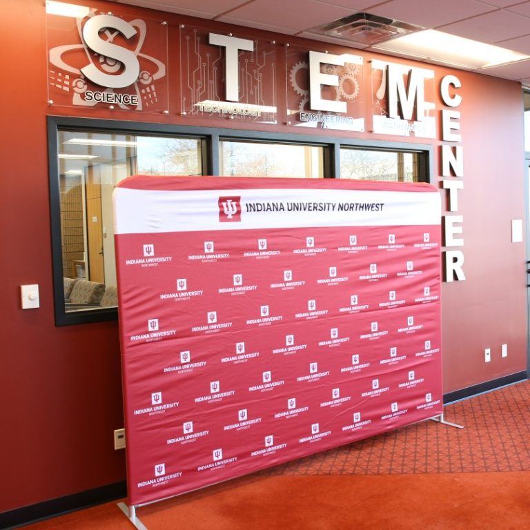 A red backdrop in front of a room that says STEM Center.