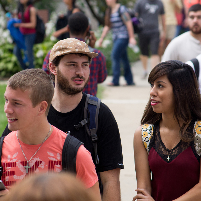 A group of students walk across a busy college campus.